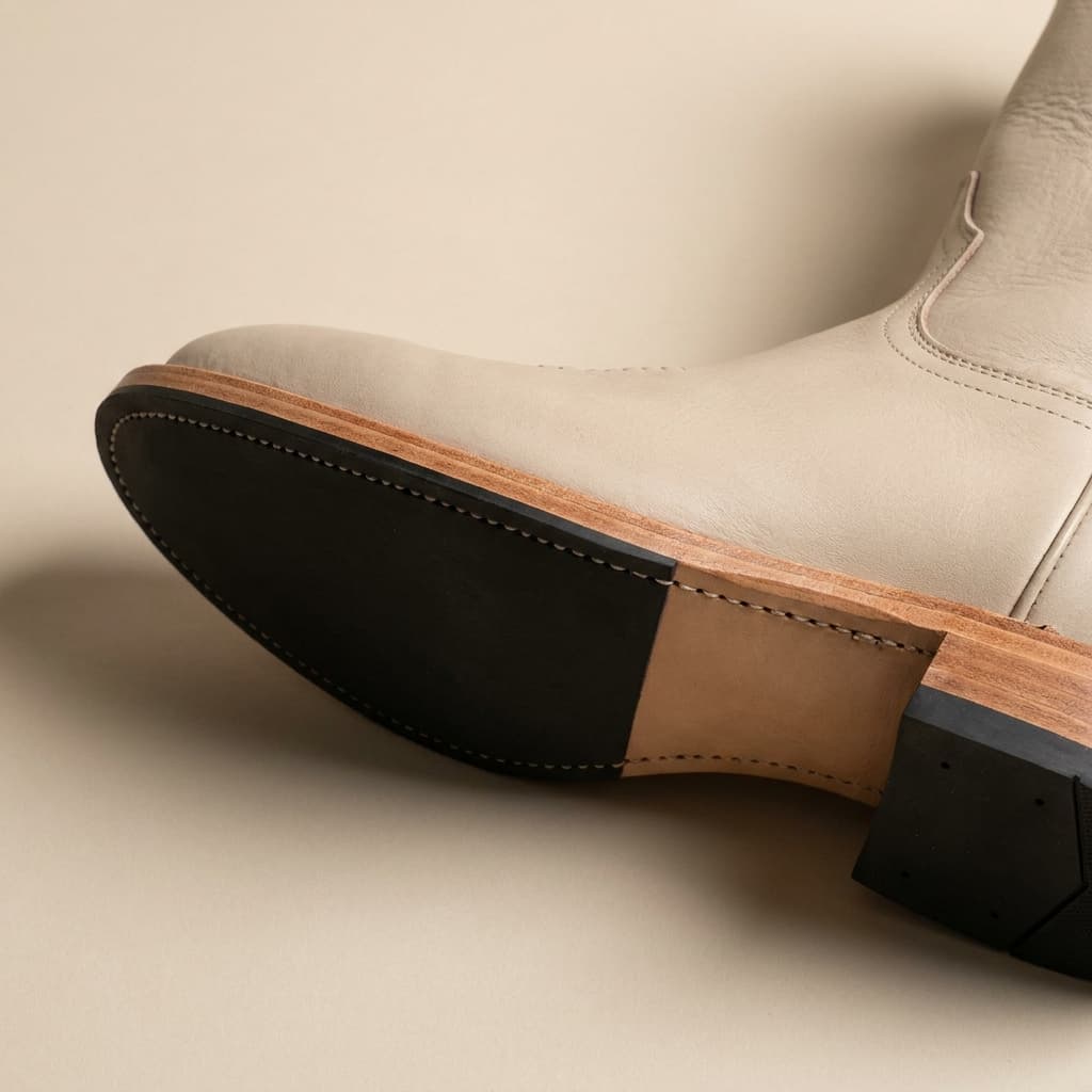 Hand-welt and sole-edge detail of The Paloma: hand-welted leather sole with vibram heel pad, full-grain bovine in stone, vegetable-tanned