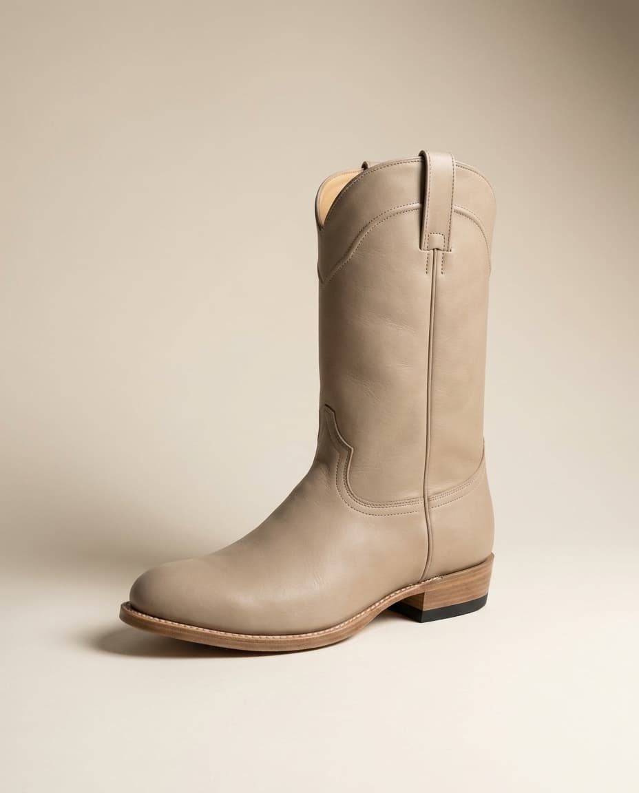 Editorial product photograph of The Paloma, a stone full-grain leather rounded-toe low-shaft western boot with a 1.25 inch walking heel and a vibram heel pad