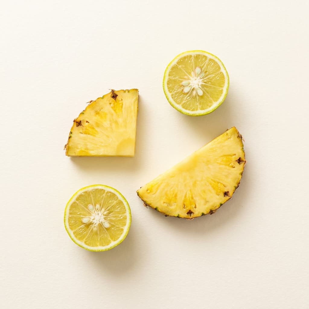 A can of Pineapple Yuzu Bloom soda among pineapple slices and yuzu rinds, soft afternoon light on cream paper.