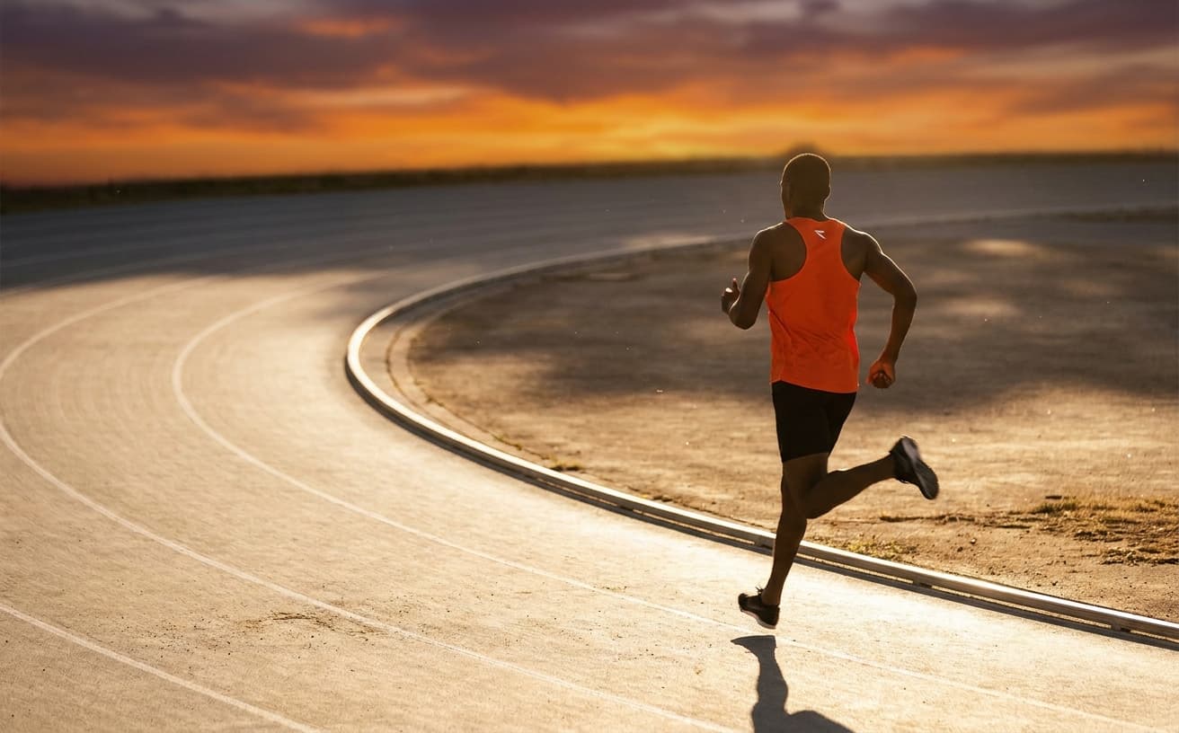 A runner mid-stride on an empty track at golden hour with motion blur on legs and arms.