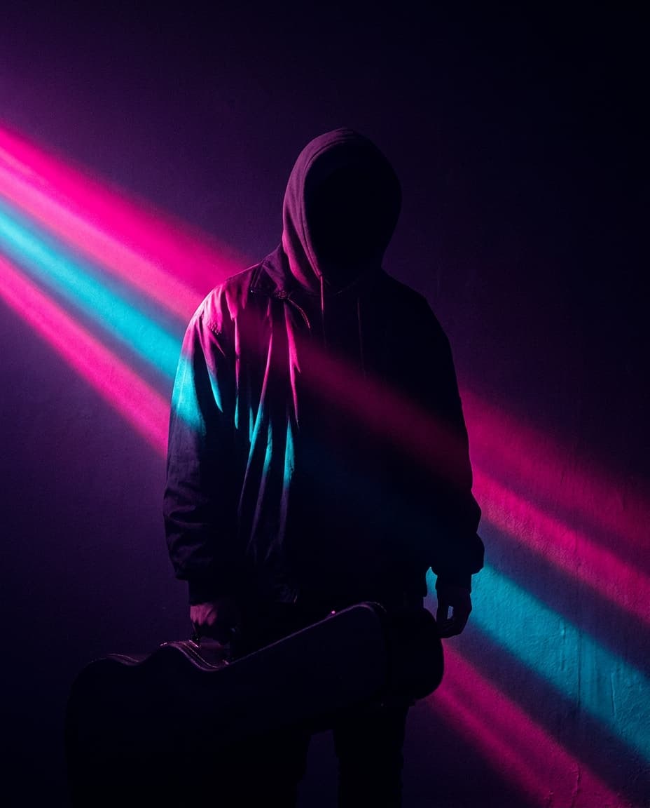 Pulse artist spotlight: a silhouette of a musician under stage lighting in pink and cyan.